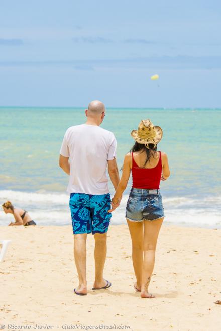 Imagem de um casal andando em direção ao mar da Praia de Itacimirim.